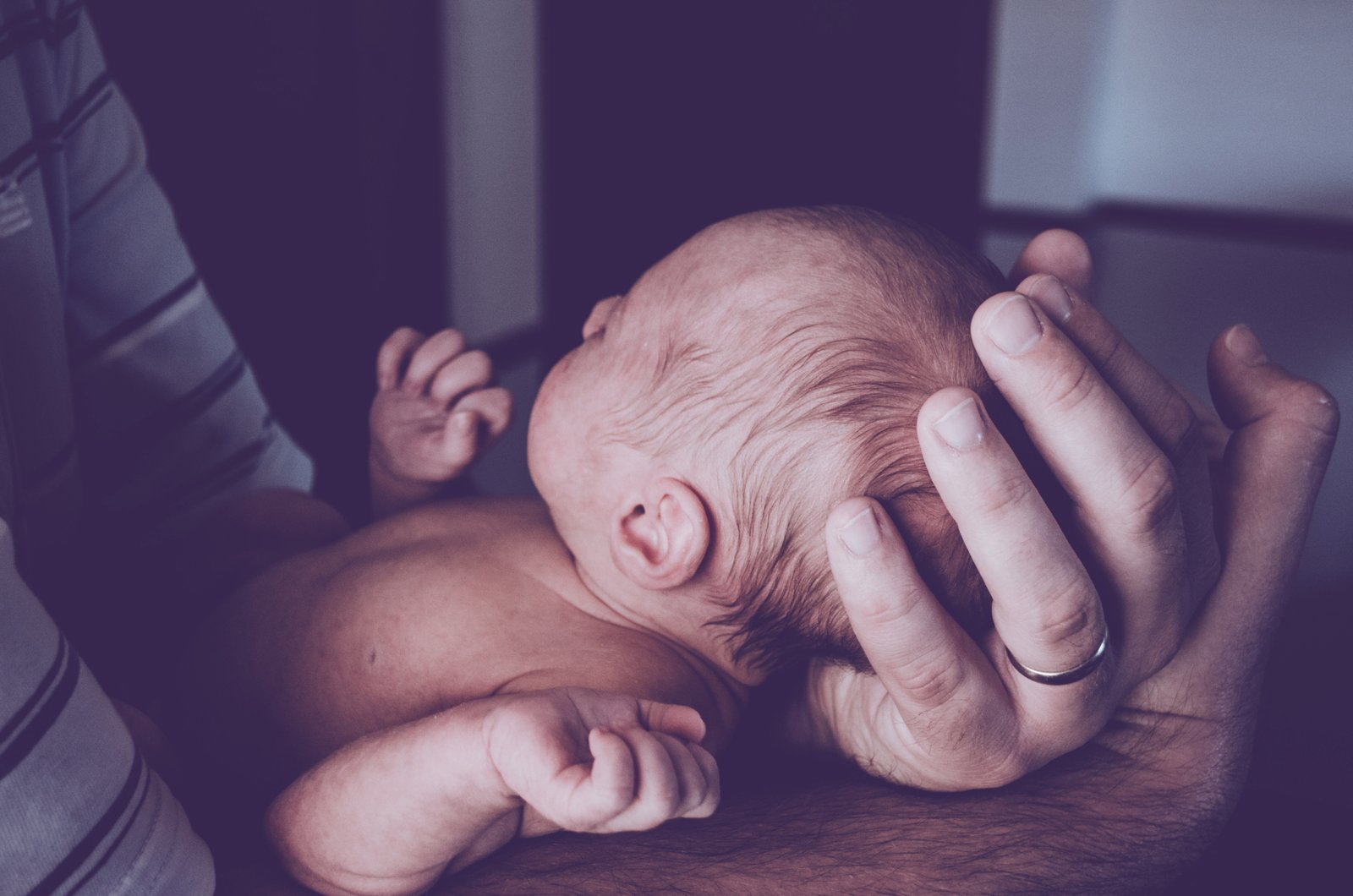 A man holds a newborn baby in his arms.